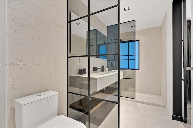 full bathroom with a walk in shower, a textured wall, and toilet