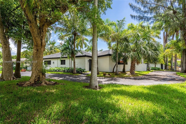 view of front of home featuring a front lawn, aphalt driveway, and stucco siding