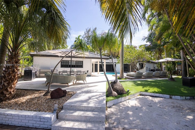 back of house with outdoor lounge area, a lawn, a patio area, and an outdoor pool