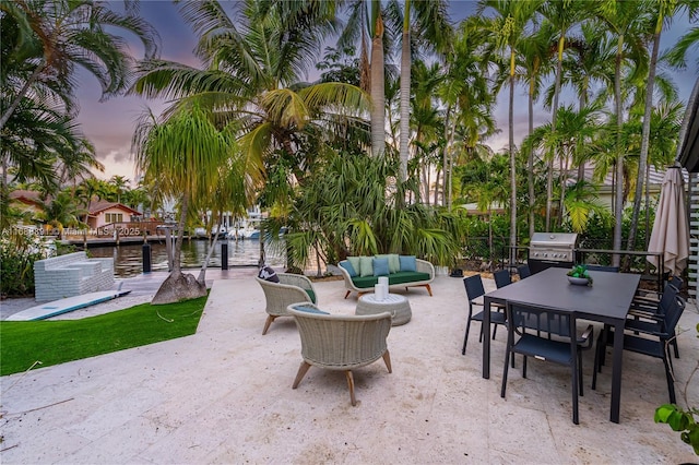 patio terrace at dusk with a water view, grilling area, outdoor lounge area, and outdoor dining space