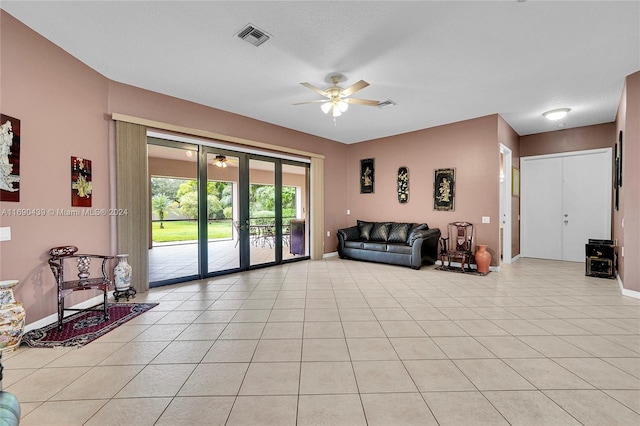 tiled living room with ceiling fan, a textured ceiling, and french doors