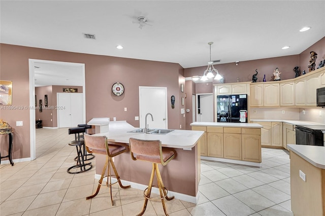 kitchen with black appliances, sink, light tile patterned floors, a kitchen island with sink, and pendant lighting