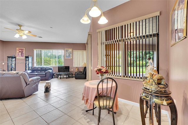 tiled living room with ceiling fan with notable chandelier