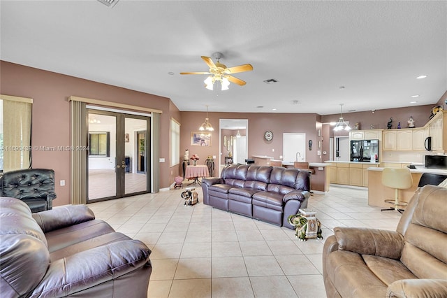 tiled living room with ceiling fan, a textured ceiling, and french doors