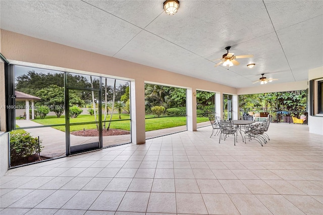 unfurnished sunroom featuring ceiling fan