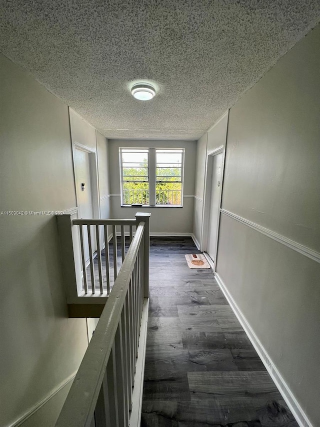 corridor featuring dark wood-type flooring and a textured ceiling