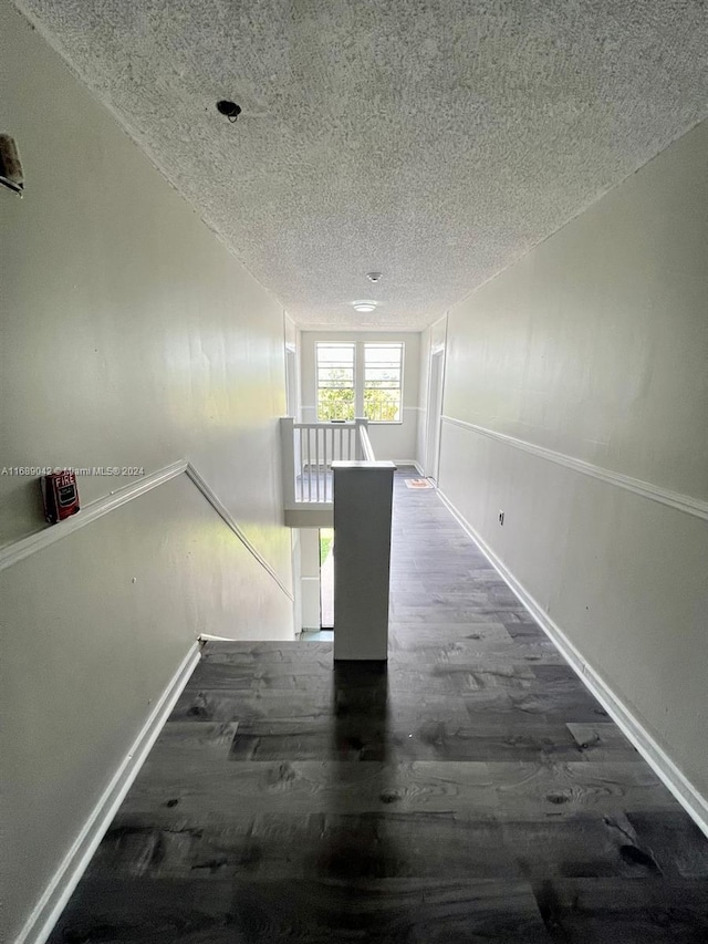 hall with a textured ceiling and dark hardwood / wood-style flooring