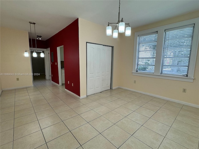 tiled empty room featuring an inviting chandelier