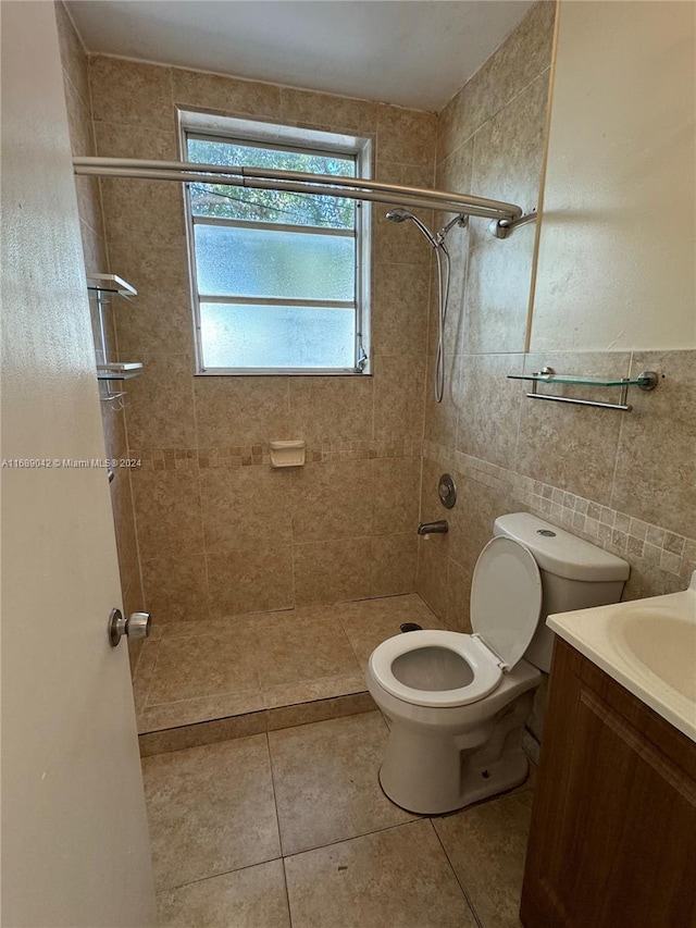 bathroom with tile walls, tile patterned floors, a tile shower, vanity, and toilet