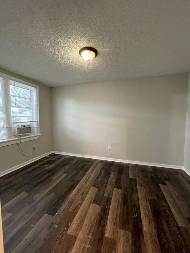 spare room with cooling unit, a textured ceiling, and dark hardwood / wood-style floors