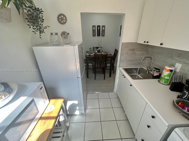 kitchen featuring white cabinetry, sink, light tile patterned floors, and white fridge