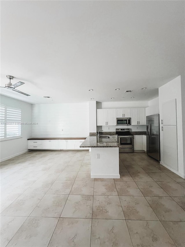 kitchen featuring dark stone counters, sink, ceiling fan, appliances with stainless steel finishes, and white cabinetry