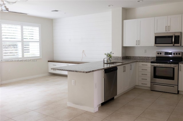 kitchen featuring kitchen peninsula, appliances with stainless steel finishes, sink, white cabinets, and light tile patterned flooring