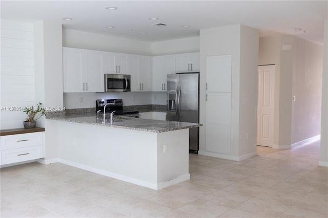 kitchen featuring kitchen peninsula, white cabinetry, dark stone countertops, and stainless steel appliances