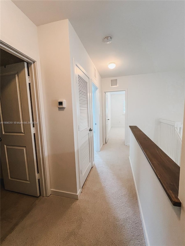 hallway featuring light colored carpet