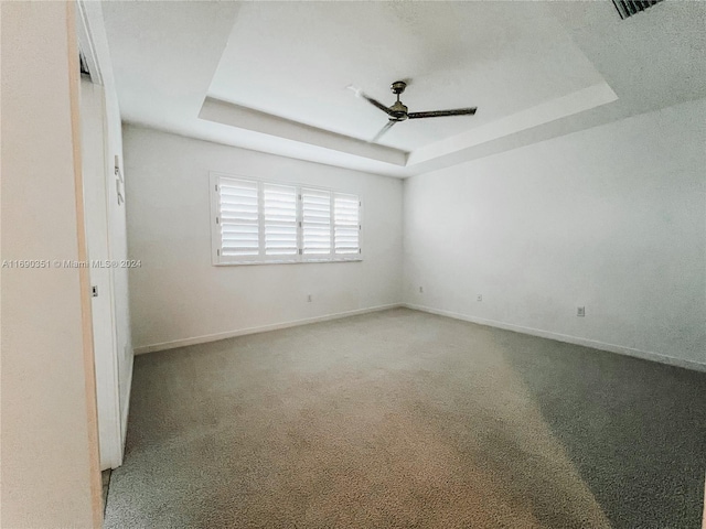 empty room featuring ceiling fan, carpet floors, and a tray ceiling