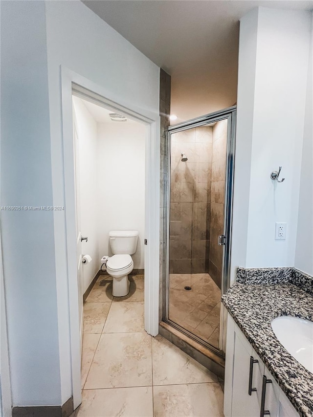 bathroom featuring vanity, a shower with shower door, and toilet