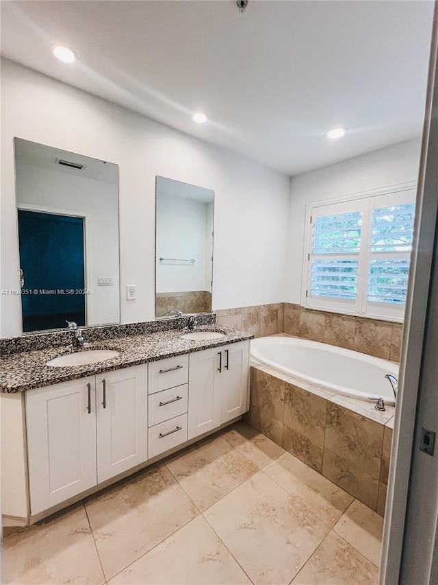 bathroom with vanity and tiled tub