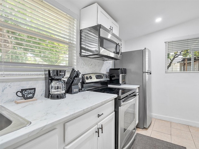 kitchen with a wealth of natural light, decorative backsplash, white cabinetry, and appliances with stainless steel finishes