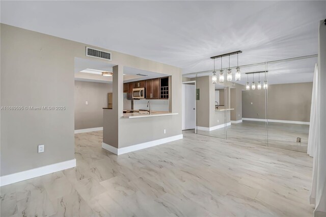 kitchen featuring stainless steel appliances, a tray ceiling, sink, and kitchen peninsula