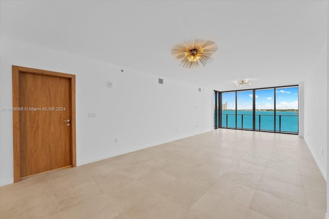 spare room featuring floor to ceiling windows and a water view