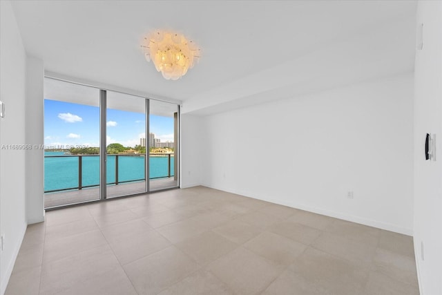 unfurnished room featuring a water view and a wall of windows