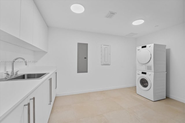 washroom with cabinets, sink, stacked washer / dryer, and electric panel