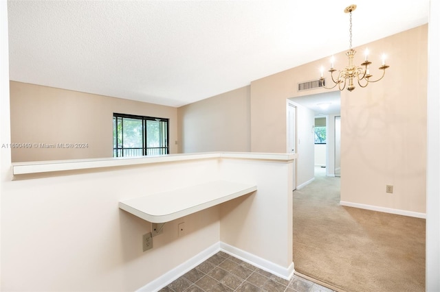 empty room with a textured ceiling, carpet flooring, and a notable chandelier