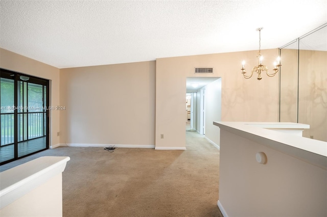 carpeted spare room with an inviting chandelier and a textured ceiling