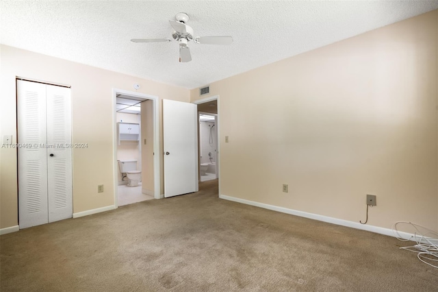 unfurnished bedroom featuring ceiling fan, connected bathroom, a textured ceiling, and carpet floors