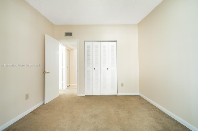 unfurnished bedroom with light carpet and a closet