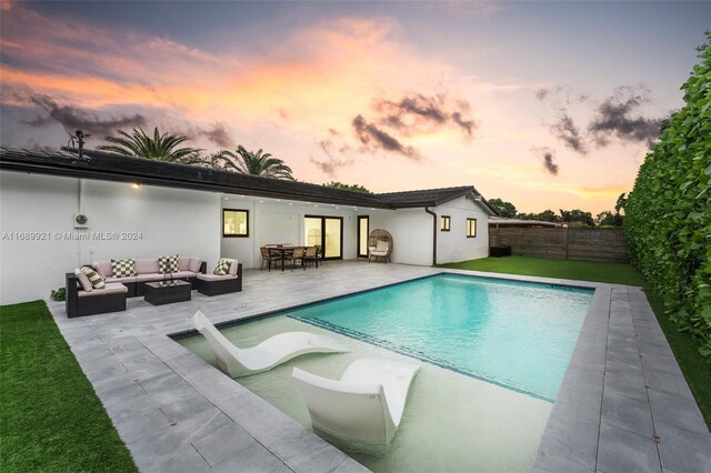 pool at dusk featuring outdoor lounge area and a patio area