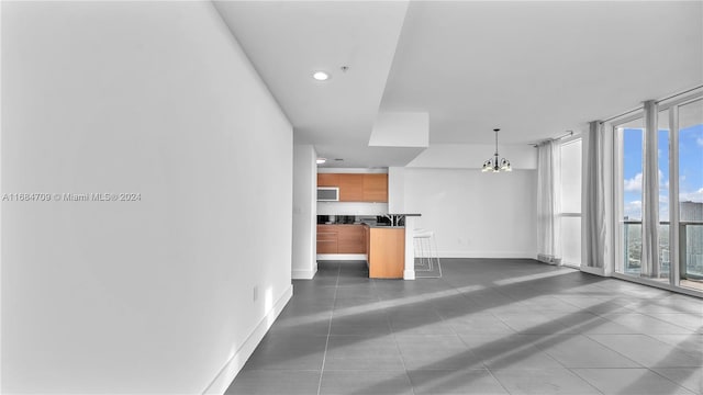 unfurnished living room with dark tile patterned flooring and an inviting chandelier