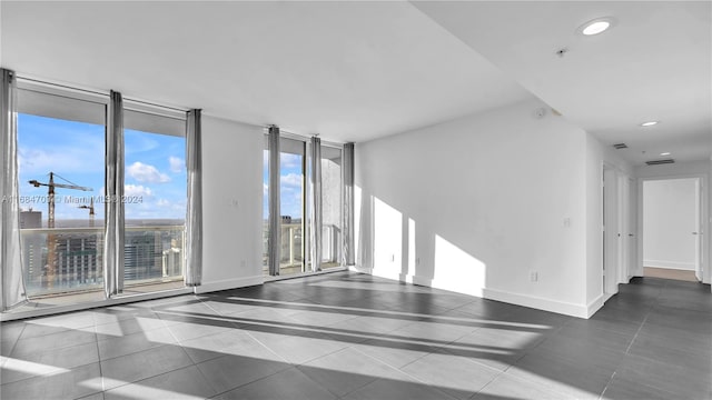 empty room featuring dark tile patterned flooring and expansive windows