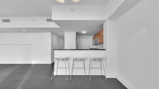 kitchen with kitchen peninsula, a kitchen breakfast bar, and dark stone counters