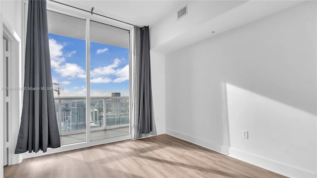 unfurnished room with light hardwood / wood-style floors and floor to ceiling windows