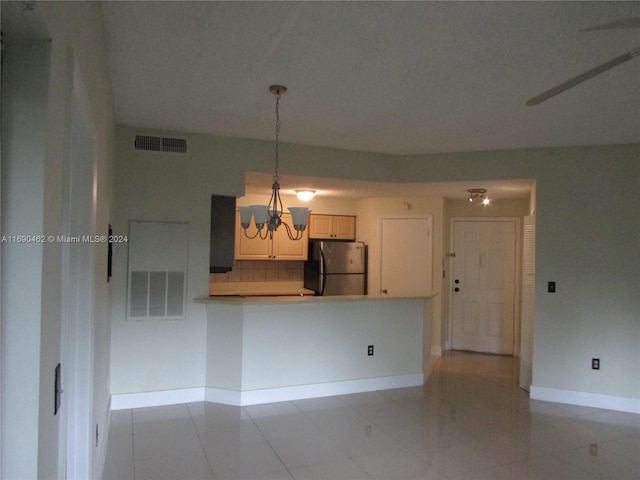 kitchen with stainless steel refrigerator, light tile patterned floors, backsplash, hanging light fixtures, and a notable chandelier