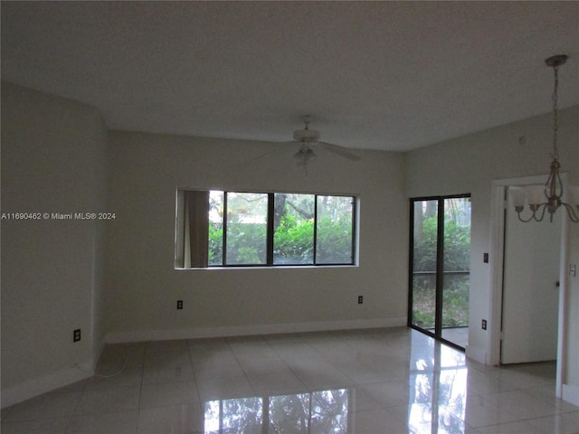 unfurnished room with light tile patterned flooring and ceiling fan with notable chandelier