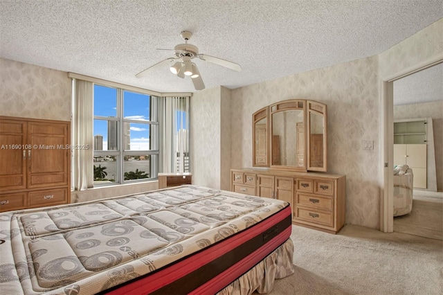 carpeted bedroom featuring wallpapered walls, a textured ceiling, and a ceiling fan