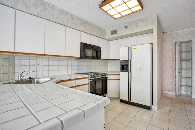 kitchen with range with electric stovetop, tile countertops, visible vents, black microwave, and white refrigerator with ice dispenser