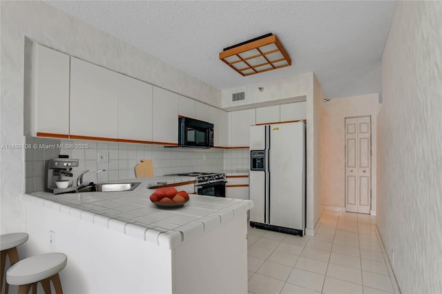 3530 Mystic Pointe Dr Unit 914, Aventura, FL 33180 - kitchen with white fridge with ice dispenser, gas stove, a sink, black microwave, and a peninsula