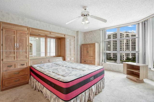 bedroom with light colored carpet, a textured ceiling, and multiple windows