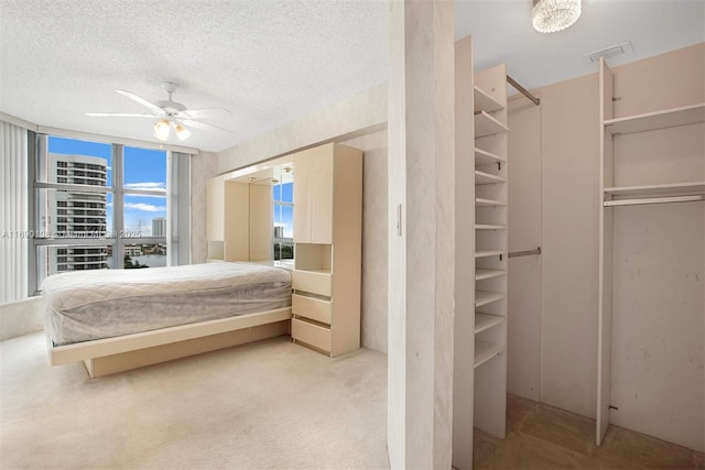 bedroom featuring light carpet, visible vents, ceiling fan, and a textured ceiling