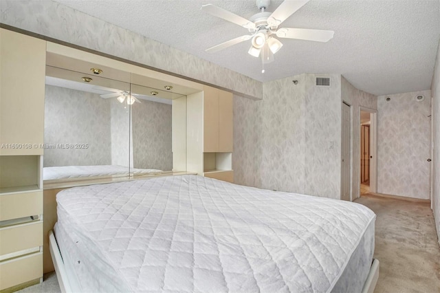bedroom featuring carpet, wallpapered walls, a textured ceiling, and visible vents