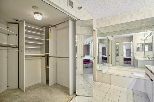 full bath with visible vents, connected bathroom, vanity, a textured ceiling, and tile patterned floors