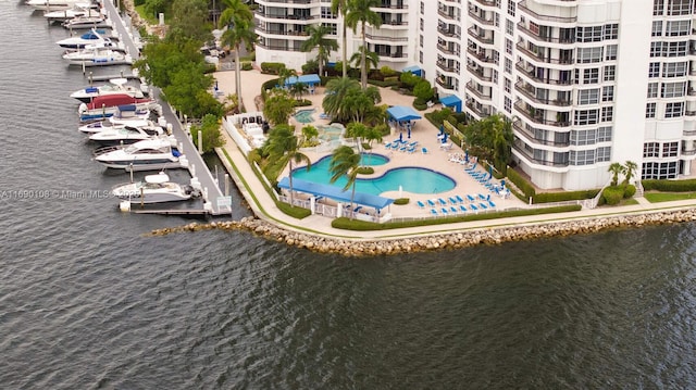 drone / aerial view of a large body of water, a pool, and apartment complex