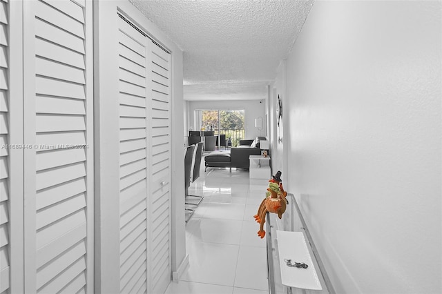 hallway featuring light tile patterned floors and a textured ceiling