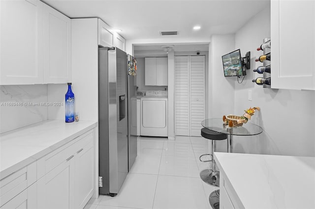 laundry area with light tile patterned flooring, cabinets, and independent washer and dryer