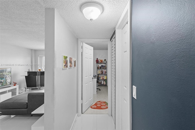 hallway with light tile patterned floors and a textured ceiling