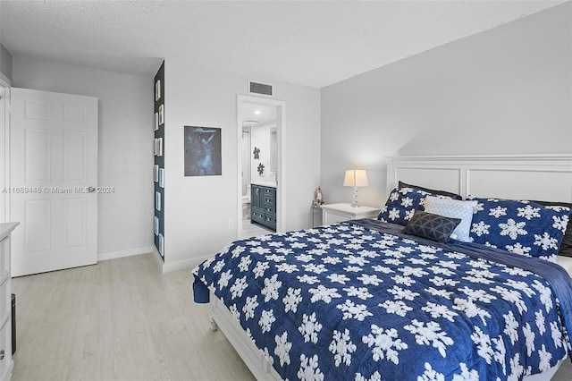 bedroom featuring a textured ceiling, connected bathroom, and light hardwood / wood-style floors